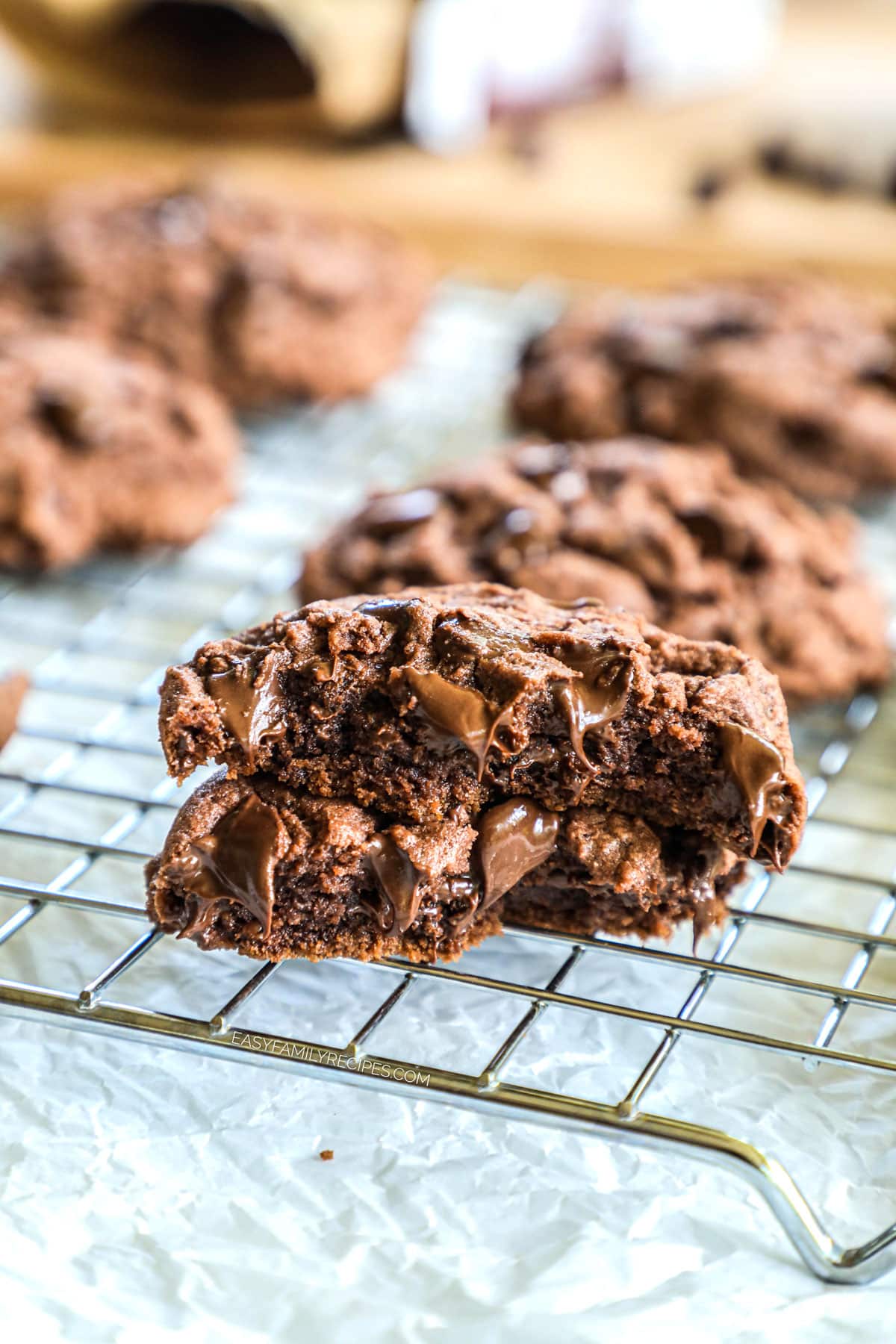 two halves of chocolate pudding mix cookies stacked on a wire cooling rack.